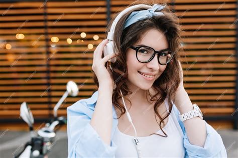 Free Photo Outdoor Close Up Portrait Of Cute Smiling Girl In Glasses Touching White Earphones