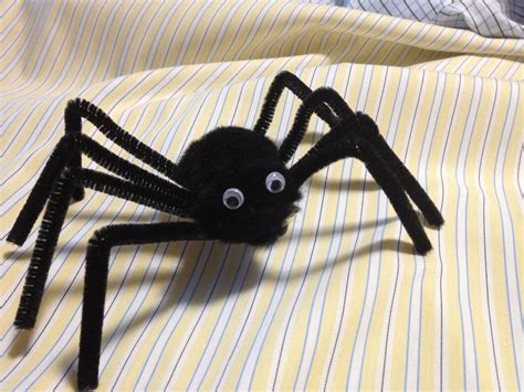 A Black Spider Is Sitting On Top Of A Yellow And White Bed Sheet With Eyes