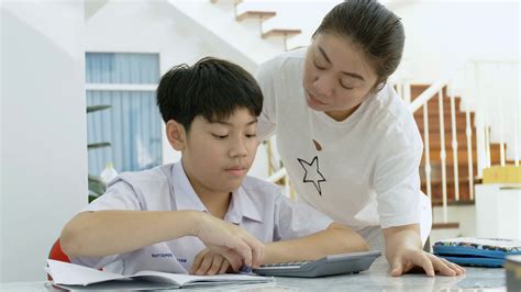 slow motion of asian mother helping her son doing homework on white table serious asian mother