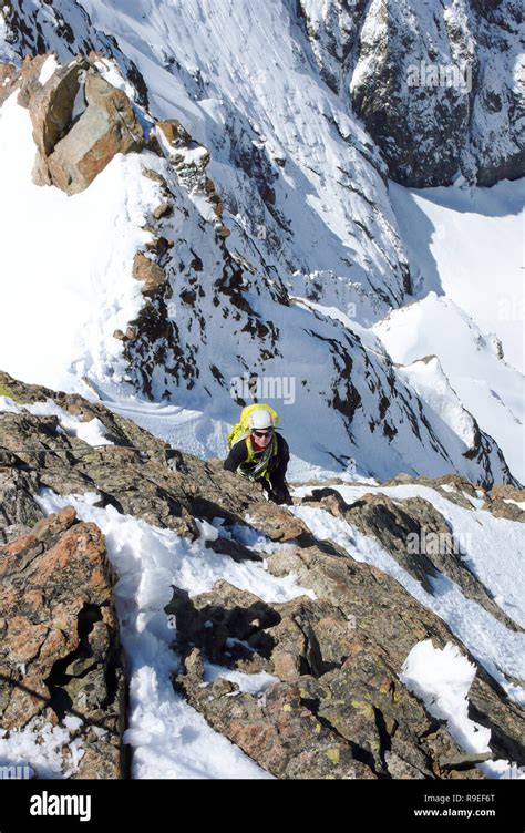 Female Mountain Climber Climbing A Mountain Peak In The Swiss Alps