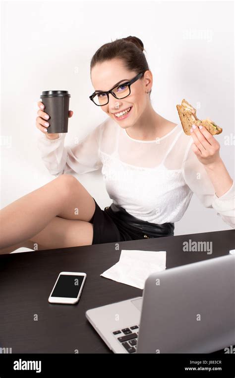 Smiling Business Woman In A Glasses Sitting On Her Workplace And Holding In Hands Coffee And