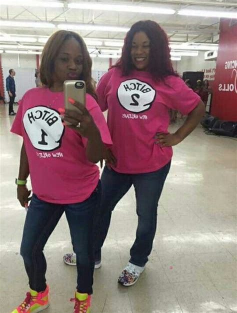 Two Women In Matching Pink Shirts Standing Next To Each Other