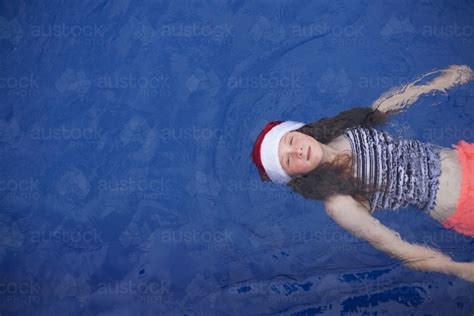 Image Of Young Girl Floats In A Pool Wearing A Festive Christmas Santa