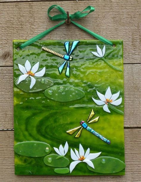 A Green Tile Wall Hanging With White Flowers And Dragonflies On Water Lillies In The Pond