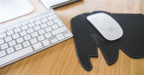 White Apple Mouse And Keyboard On The Black Elephant Pad · Free Stock Photo