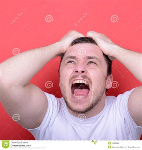 Portrait Of Angry Man Screaming And Pulling Hair Against Red Background