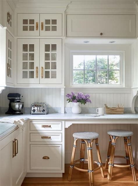 Huge selection of styles and wood types. Under a white shaker overhead cabinet, a window is flanked ...