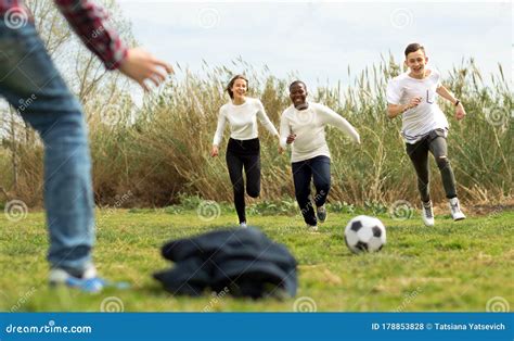 Multi Nationalities Teenagers Play Football Through Green Lawn In