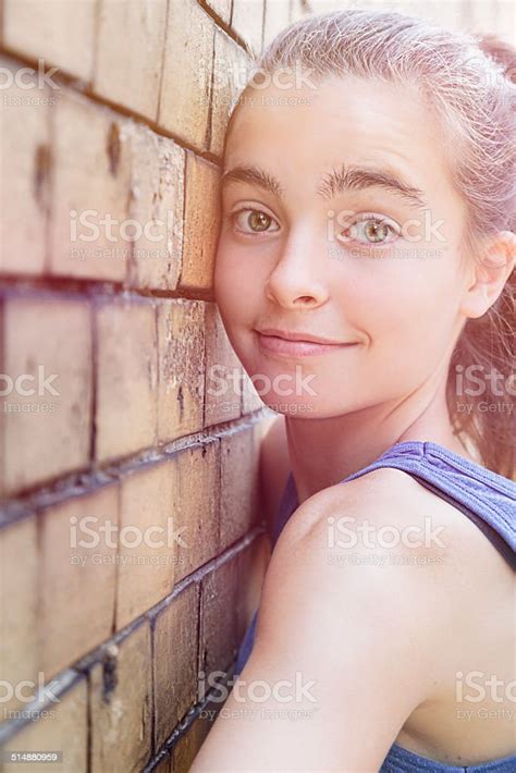 Smiling Teenager Girl Leaning Against A Brick Wall Stock Photo