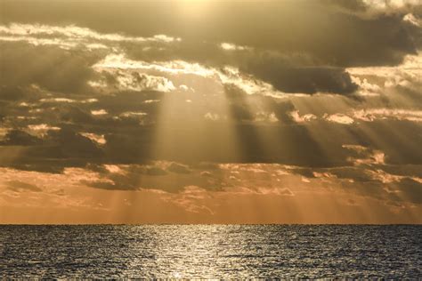 Sunbeams Shining Through Clouds Over Sea During Sunset Stockfreedom