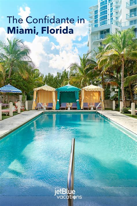 An Outdoor Swimming Pool Surrounded By Palm Trees And Umbrellas With