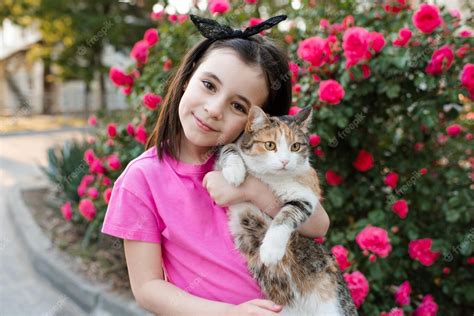 Premium Photo Cute Kid Girl Holding Cat Posing Over Blooming Rose