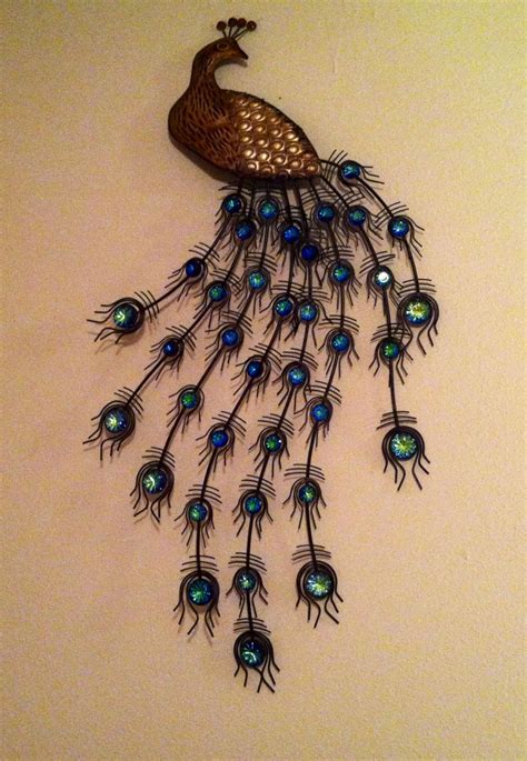 a metal peacock with blue and green feathers on it s tail is mounted to the wall