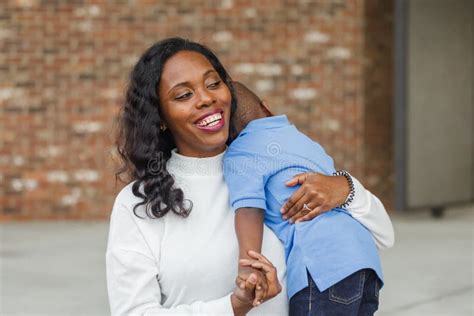 A Beautiful African American Mom Giving Her Toddler Son A Hug Stock