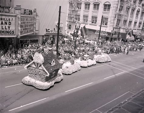 A Parade With Floats In The Street And People Watching