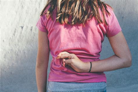 Young Teen Tween Girl Crossing Her Fingers Behind Her Back Del Colaborador De Stocksy