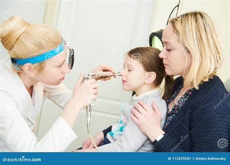Female Doctor Of Ent Ear Nose Throat At Work Examining Girl Nose Stock