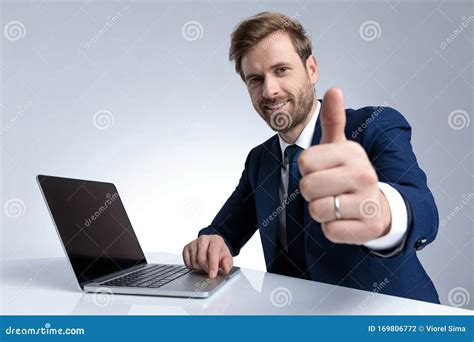 Businessman Giving A Thumbs Up And Working On His Laptop Stock Photo