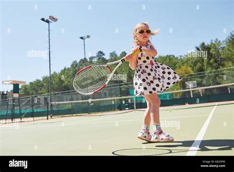 Cute Little Girl Playing Tennis On The Tennis Court Outside Stock Photo
