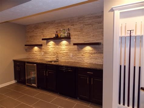 CMH Builders Wet bar with floating shelves on stacked stone wall