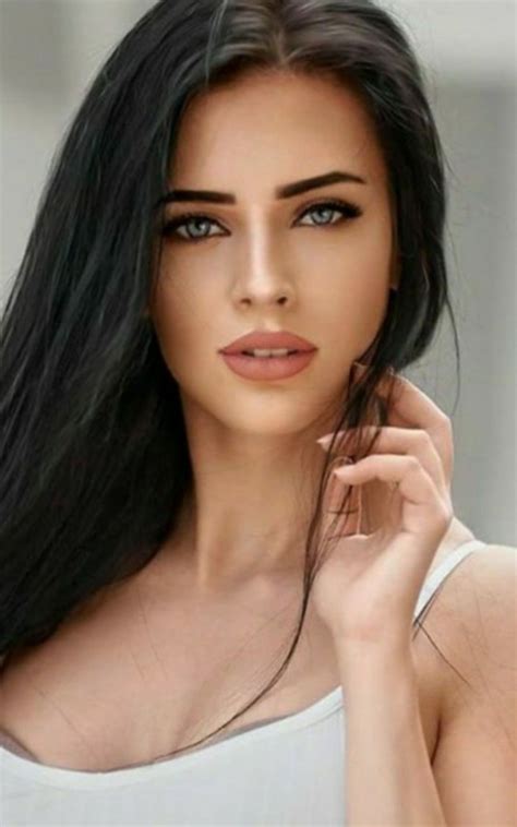 A Woman With Long Black Hair And Blue Eyes Is Posing For The Camera