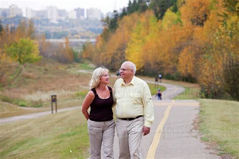 Mature Married Couple Walking Together In Park During Fall Season