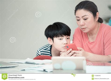 Asian Boy With Mother Teaching And Learning Your Homework At Home Stock