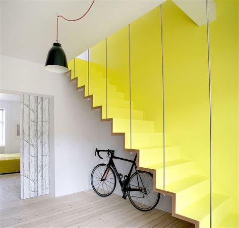 There Is A Bike On The Wooden Floor Next To The Yellow Stairs In This Room