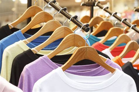Multicolored T Shirts On Wooden Hangers In Store Front View Stock