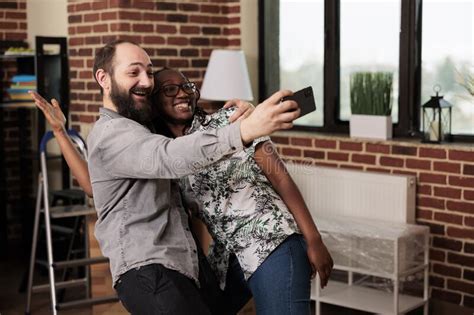 Diverse Husband And Wife Having Fun With Pictures On Smartphone Stock