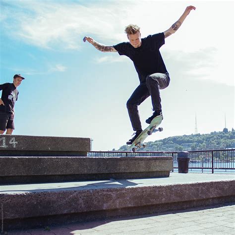 A Young Man Performs A Jump On A Skateboard While Another Watches Him