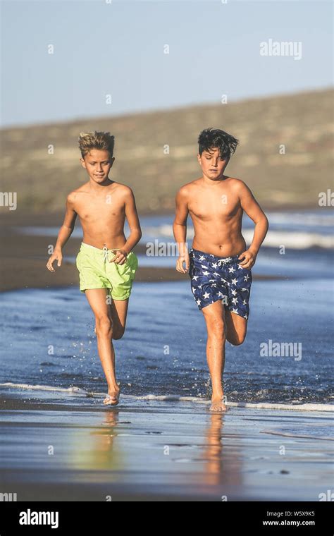 Portrait Of Two Young Boys Running On The Beach After The End Of School