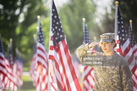 American Female Soldier Saluting In A Field Of American Flags High Res