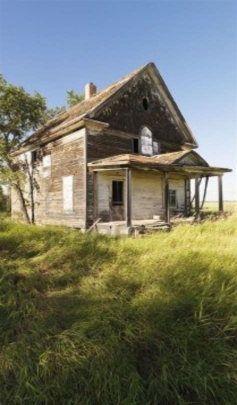 An Old Abandoned House Sitting In The Middle Of A Grassy Field With