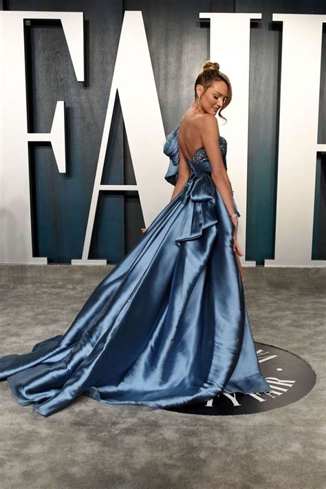 A Woman In A Blue Dress Is Standing On The Carpet With Her Back Turned