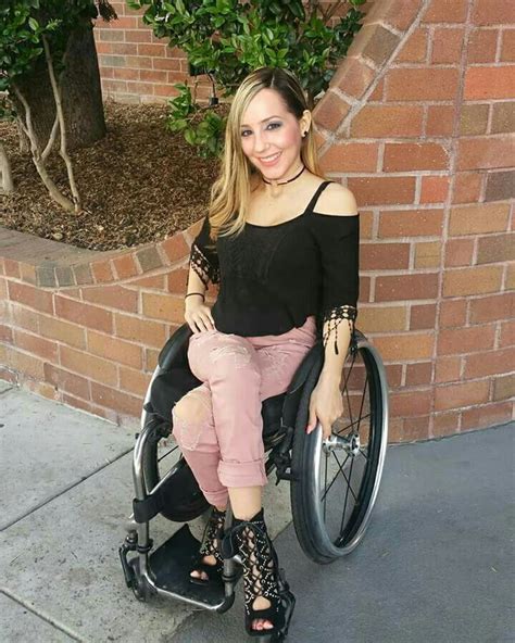 A Woman Sitting On Top Of A Wheel Chair Next To A Brick Wall And Trees