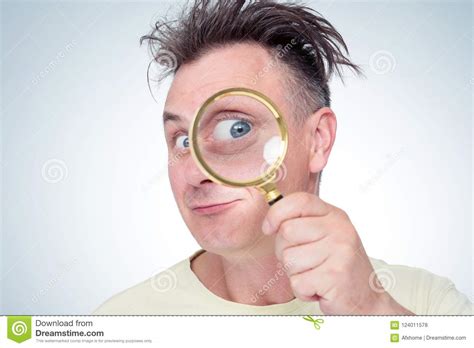 Funny Young Man Looking Through Magnifying Glass On Light