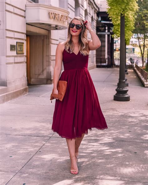 A Woman In A Red Dress Is Walking Down The Street With Her Hand On Her Head