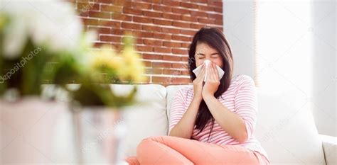 Asian Woman Blowing Her Nose On Couch Stock Photo By Wavebreakmedia