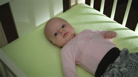 Top Side View Of Adorable Baby In Pink Cloth Lying On Bed And Moving
