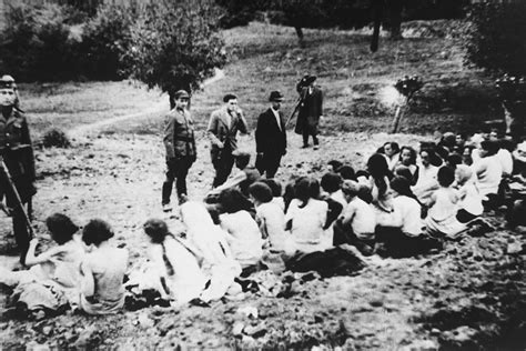 German Police And Auxiliaries In Civilian Clothes Look On As A Group Of Jewish Women Are Forced
