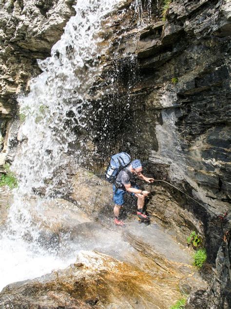 Mountain Climber Hiking Under A Waterfall On A Rocky Hiking Trail Stock