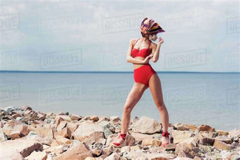 Beautiful Elegant Girl Posing In Red Bikini And Silk Scarf On Rocky