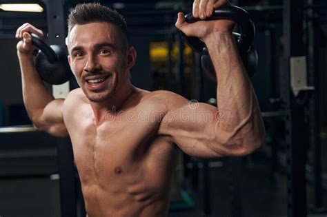 Delighted Young Sportsman Lifting Weights In The Gym Stock Image