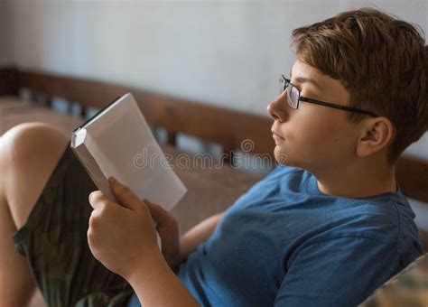 A Teenager In Glasses Is Reading A Book At Home Stock Image Image Of