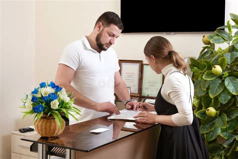 Man Welcoming Young Woman Client At Office Reception Desk Stock Photo