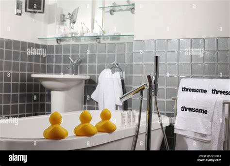 Three Rubber Ducks Sit On The Side Of A Bath In A Suite Threesome
