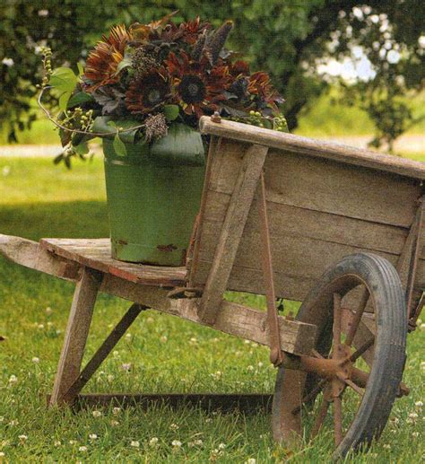 An Old Wooden Wheelbarrow With Flowers In It