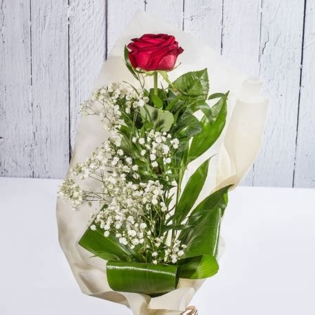 Composizione alta di fiori gialli e bianchi. Una rosa rossa a gambo lungo con verde decorativo e tessuto