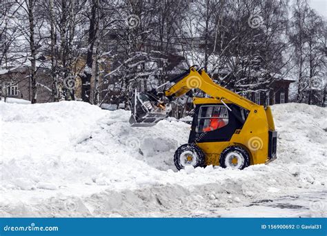 A Yellow Snow Grader Cleans Snow Covered Roads On A City Street